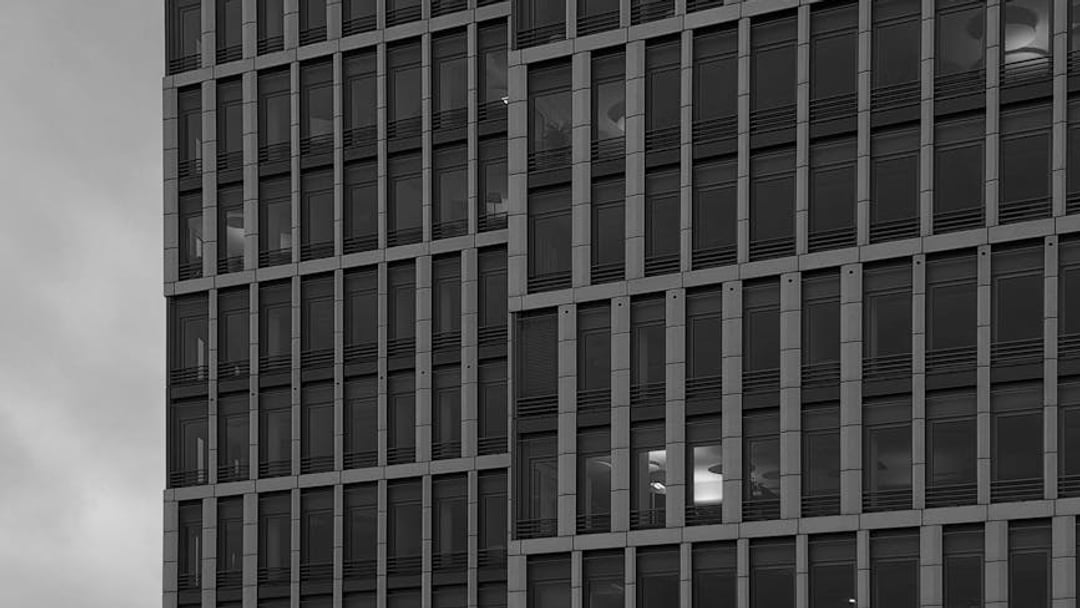 Close-up of a modern office building facade with glowing lights seen through windows at dusk, illustrating Bitcoin