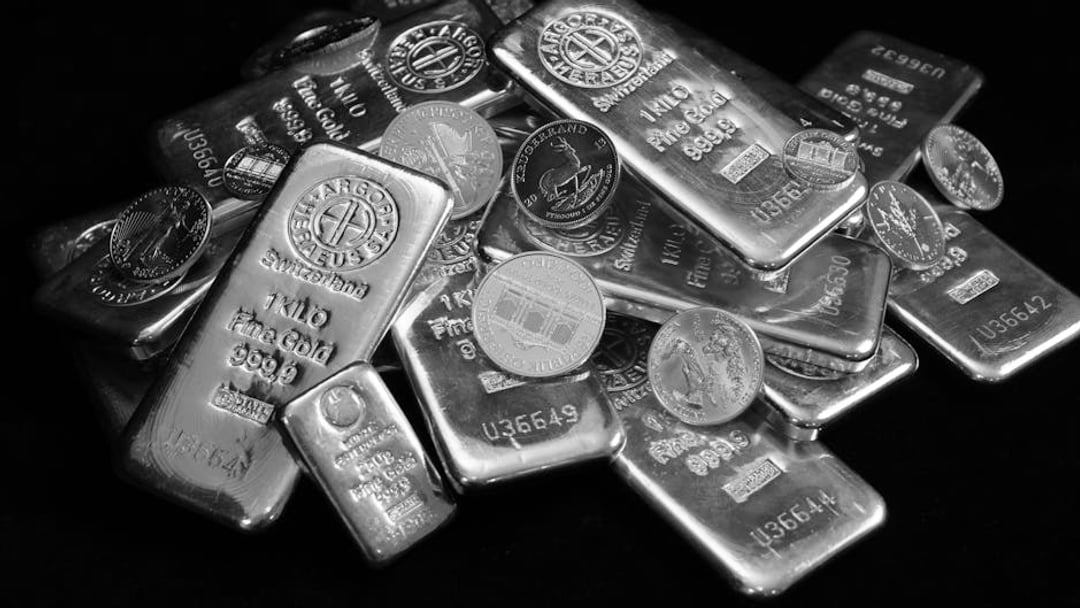 A collection of shining gold bars and coins symbolizing wealth and investment — context for gold price Iran war (energy