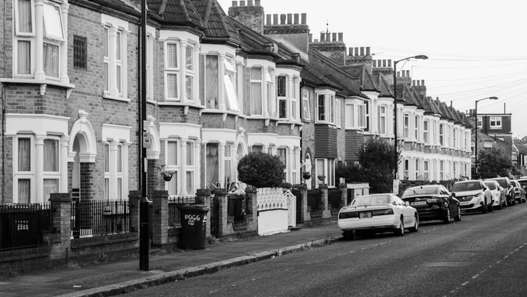 Charming view of traditional London terraced houses and parked cars along a quiet street at dusk, illustrating London stamp