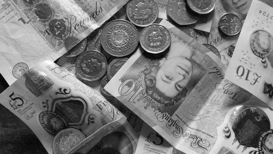 Close-up collection of British Pound notes and coins, showcasing UK currency, illustrating Bank of England QE cost