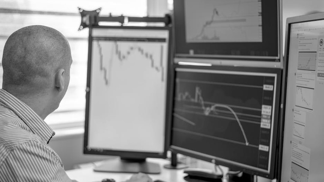 Trader analyzing financial data on multiple monitors in an office setting, illustrating BlackRock tokenization