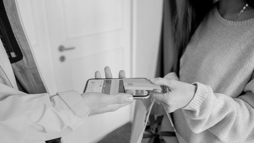 A close-up view of contactless payment transaction using a mobile phone and credit card indoors, illustrating LSE growth