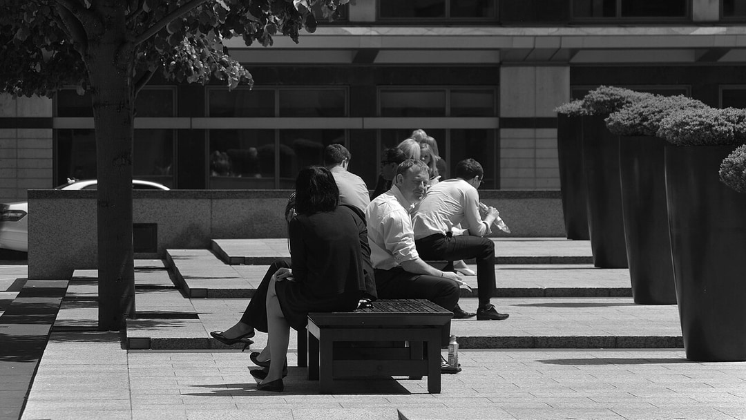 Office workers eat lunch in the sunshine of Columbus Courtyard in Canary Wharf, illustrating UK permanent jobs