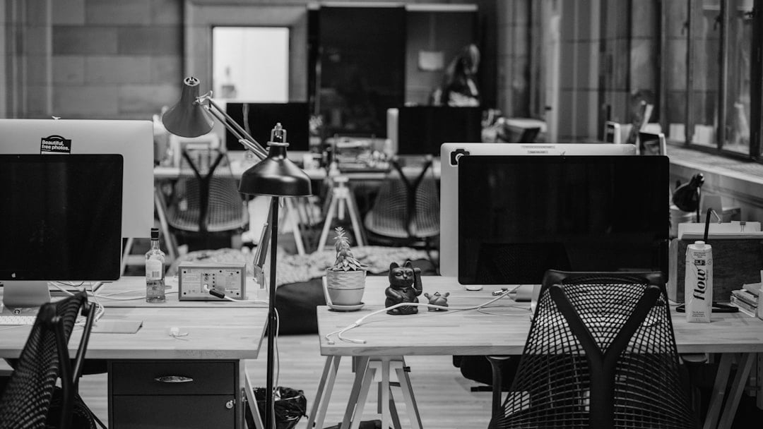 turned off flat screen monitors on top of beige desks, illustrating UK PMI job cuts