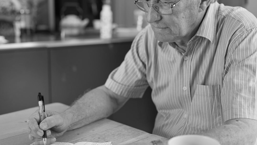 a man sitting at a table writing on a piece of paper, illustrating UK State Pension G7