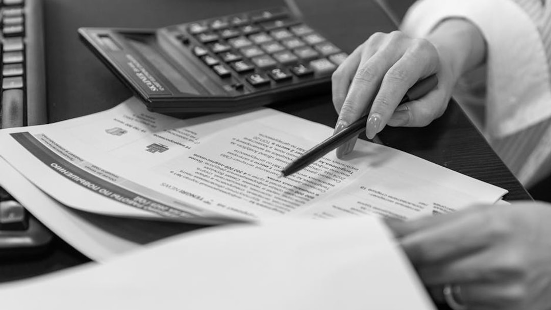 Close-up of a woman's hand reviewing financial documents with a calculator, illustrating UK State Pension G7